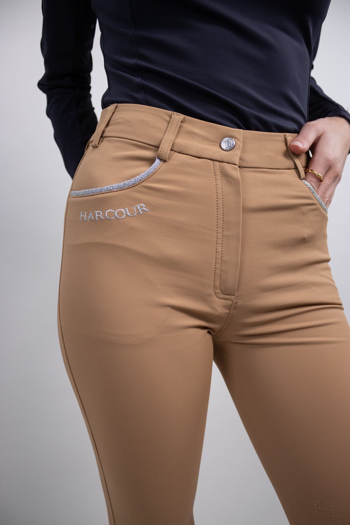 Tan breeches from the front with a silver trimmed pocket, button closure and HARCOUR embroidery