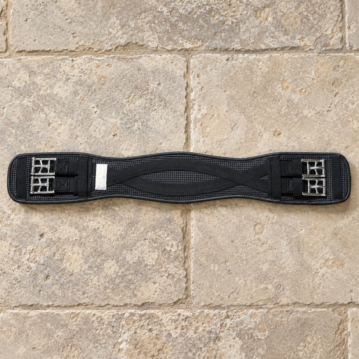 Black Lettia mesh Clik dressage girth lying flat on limestone flagstones