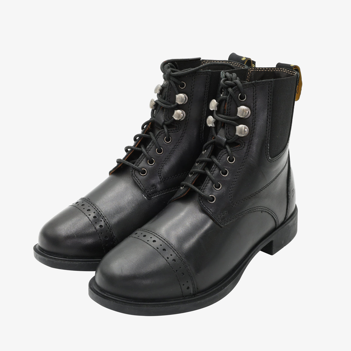 Pair of black lace-up paddock boots, angled front view of the laces, silver tone hooks and brogue cap toes