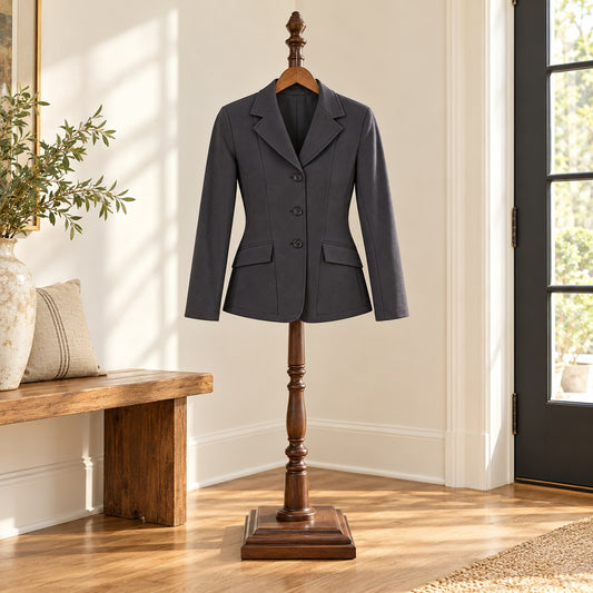 Dark gray three button show coat with notch lapels and flap pockets, on a wooden valet stand in an entry hall