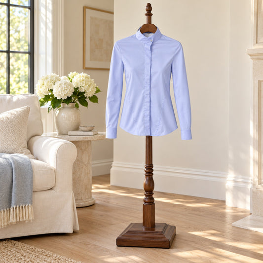 Light blue long sleeve button up shirt with a stand collar, on a wooden valet stand in a sitting room