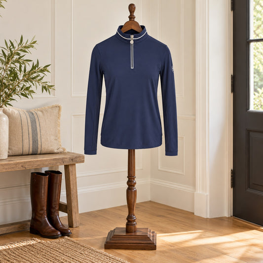 Navy long sleeve quarter-zip sun shirt with white collar piping, on a wooden valet stand in an entry hall