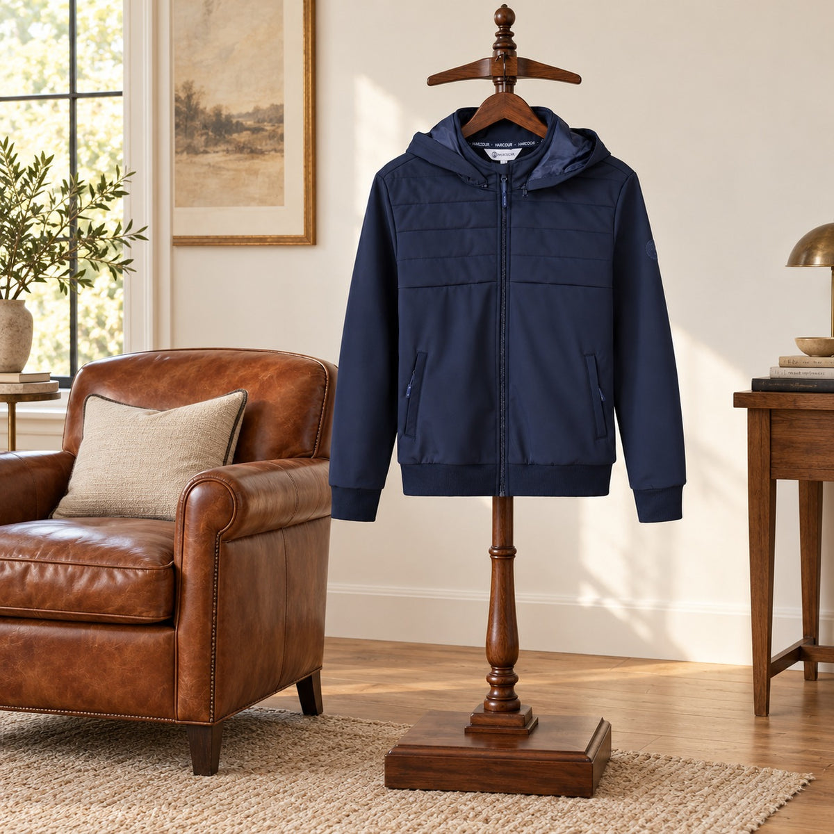 Navy hooded zip jacket with a quilted upper panel, displayed on a wooden valet stand in a study