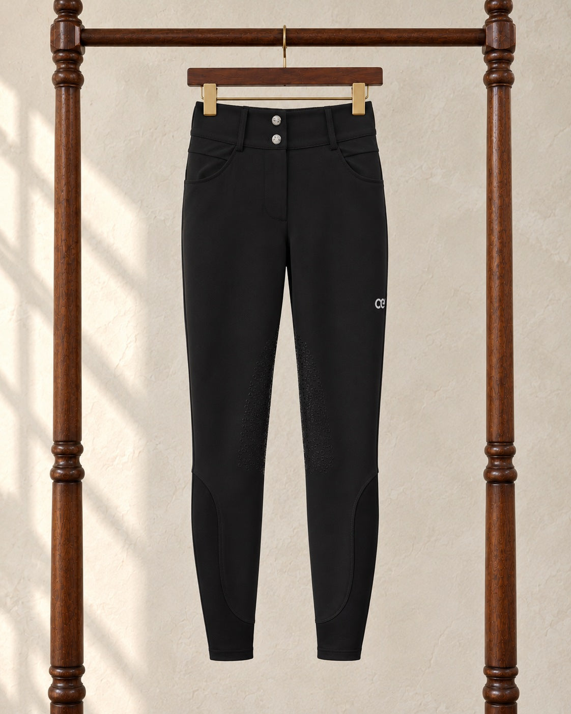 Black American Equus performance breeches on a clip hanger on a walnut garment rack