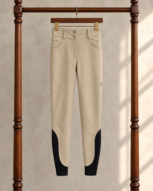 Tan American Equus performance breeches on a clip hanger on a walnut garment rack