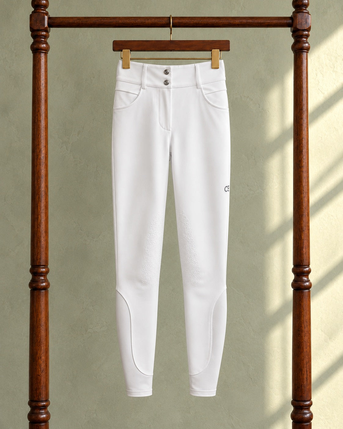 White American Equus performance breeches on a clip hanger on a walnut garment rack