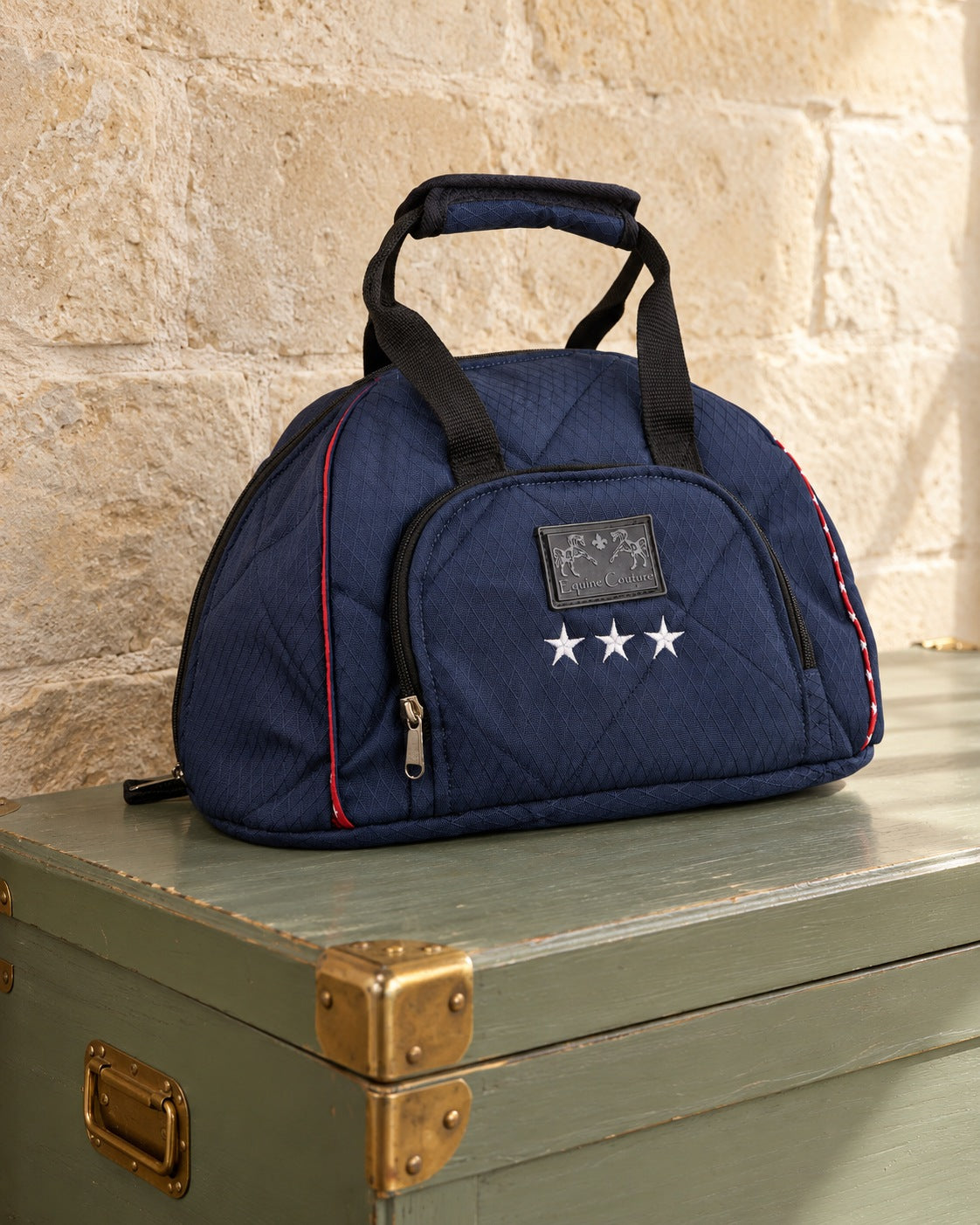 Navy quilted Equine Couture Super Star helmet bag on a sage green tack trunk against a limestone wall