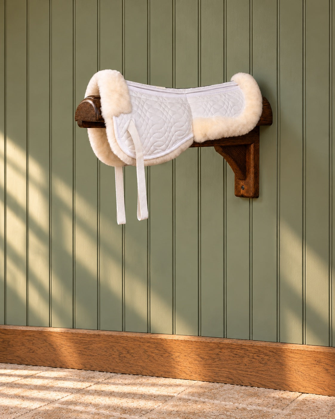 White Europa sheepskin 4-shim half pad on a wooden wall bracket against a green panelled wall