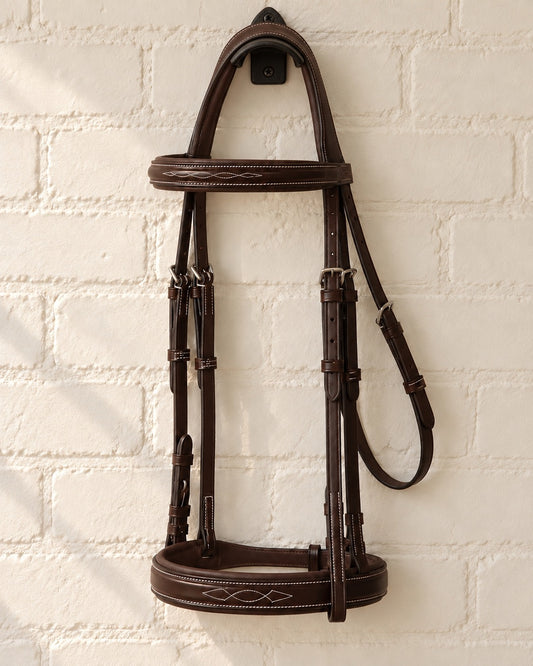 ExionPro Hercules hunter bridle hung on a black cast iron bridle bracket against a white brick wall