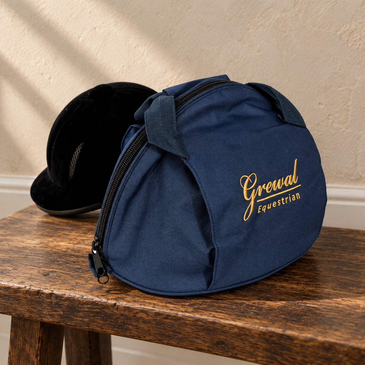 Grewal helmet bag with a black velvet riding helmet on an oak bench