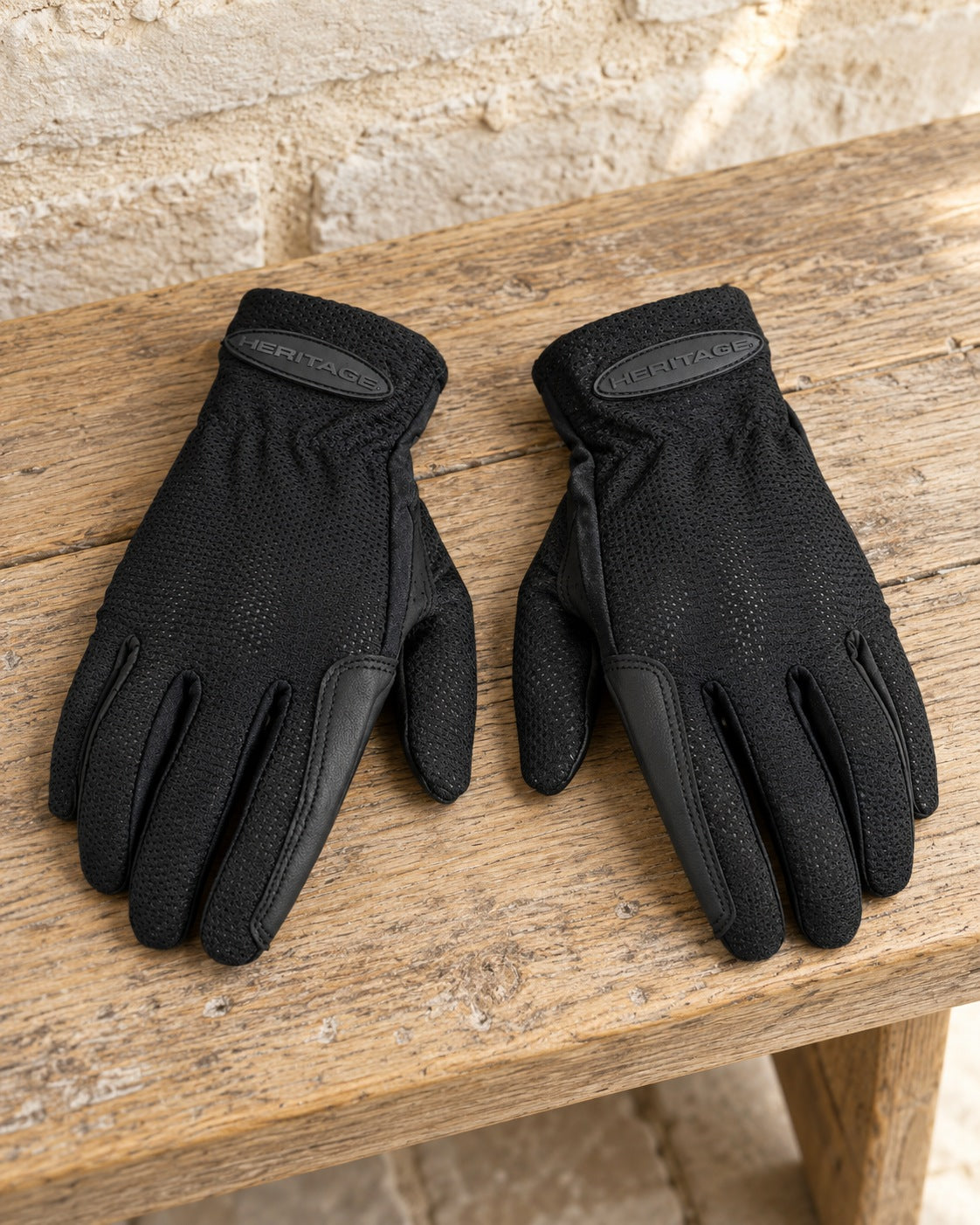 Pair of black Heritage Pro-Flow summer show gloves on an oak bench