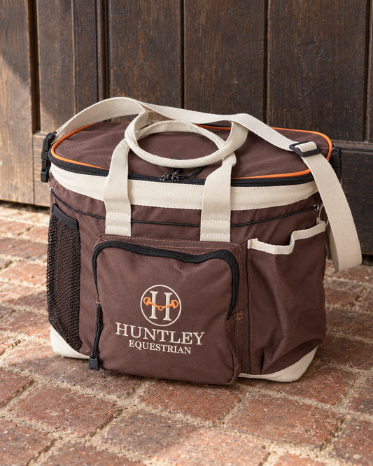 Brown Huntley Equestrian deluxe grooming bag on a brick stable floor in front of an oak stall door