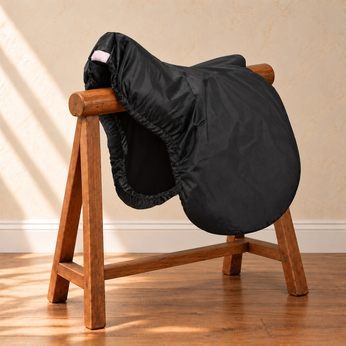 Black Lettia waterproof saddle cover on a saddle resting on a wooden saddle horse