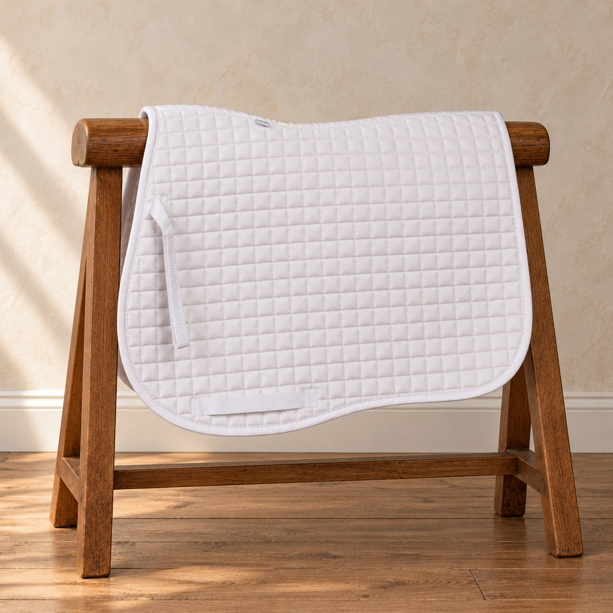 White Ovation Coolmax jumper saddle pad draped over a wooden saddle horse