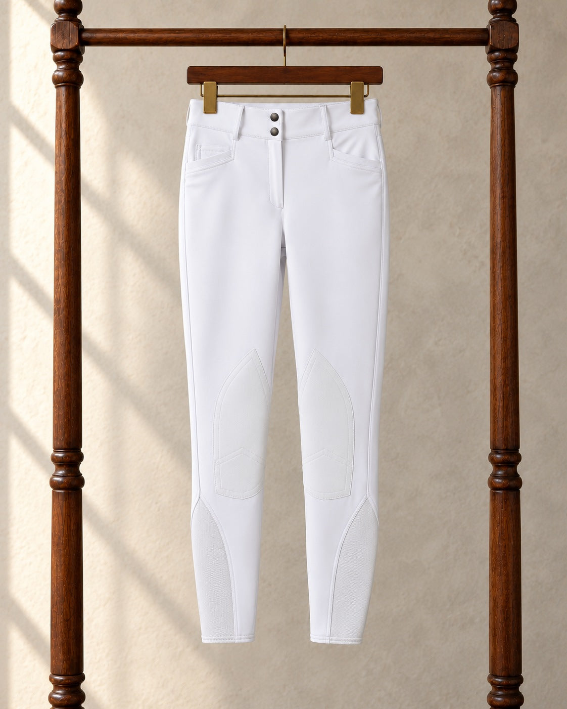 White Ovation Dynamic Hunter knee patch breeches on a clip hanger on a walnut garment rack