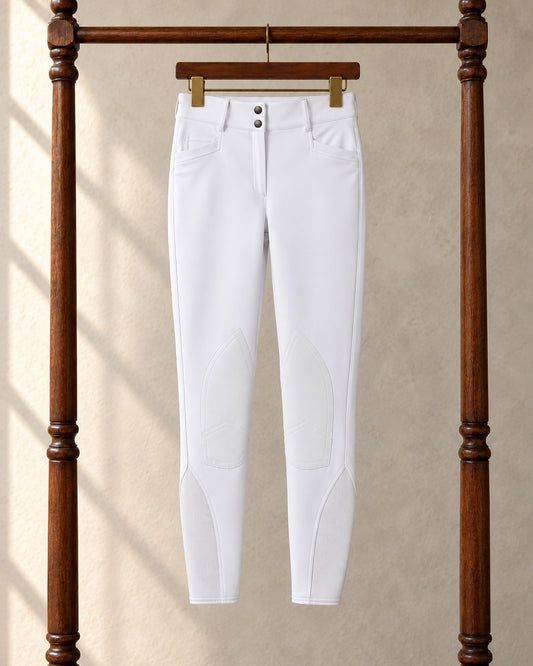 White Ovation Dynamic Hunter knee patch breeches on a clip hanger on a walnut garment rack