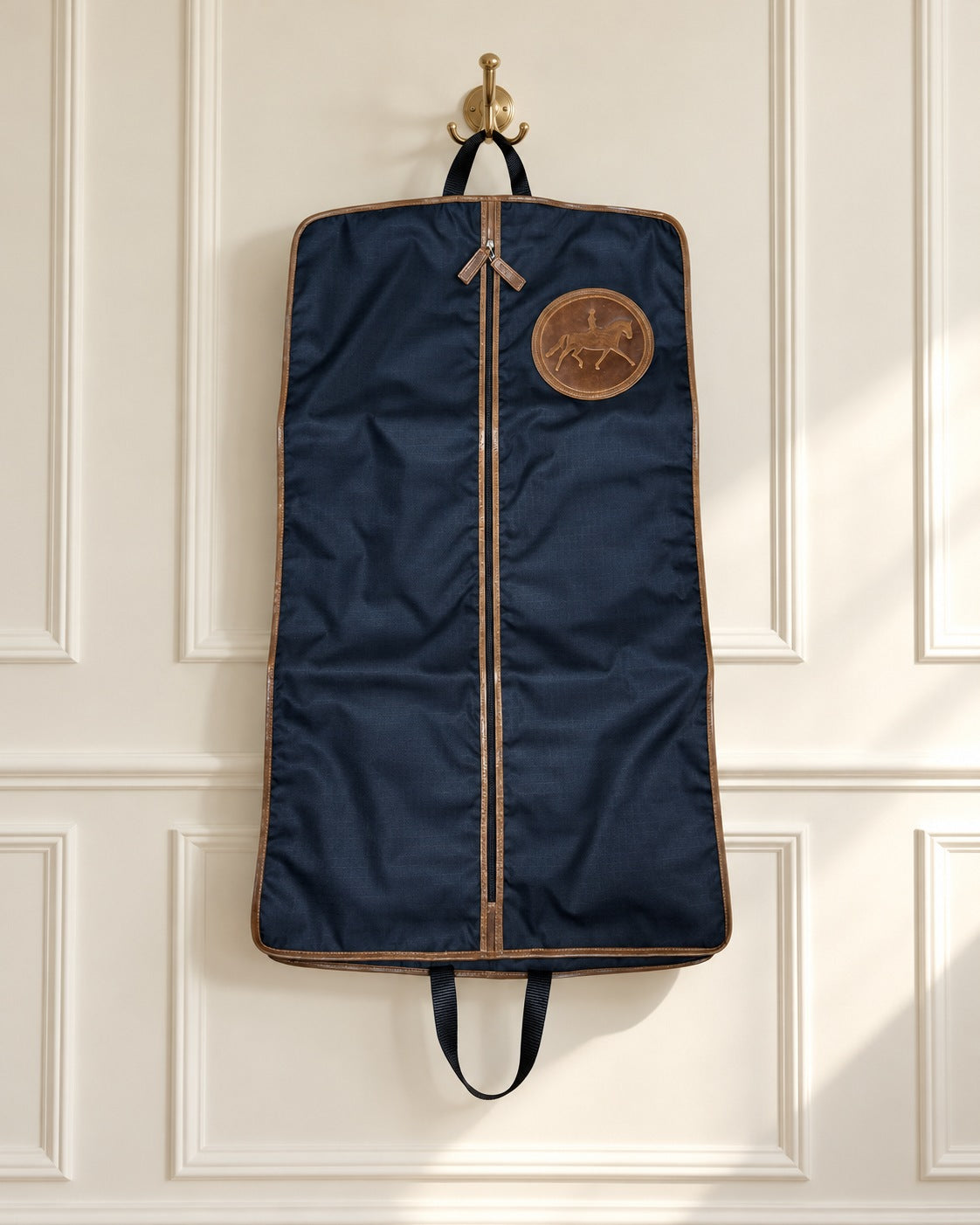Navy Tucker Tweed Tryon garment bag with leather trim hanging from a brass hook