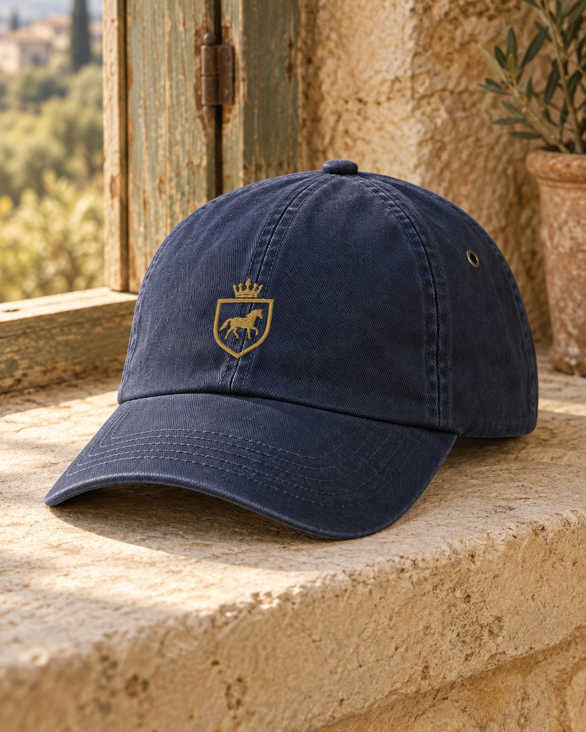 Canter & Crest Signature Crest Cotton Cap in Navy, gold embroidered Signature crest on the front panel, on a limestone sill in a Mediterranean farmhouse