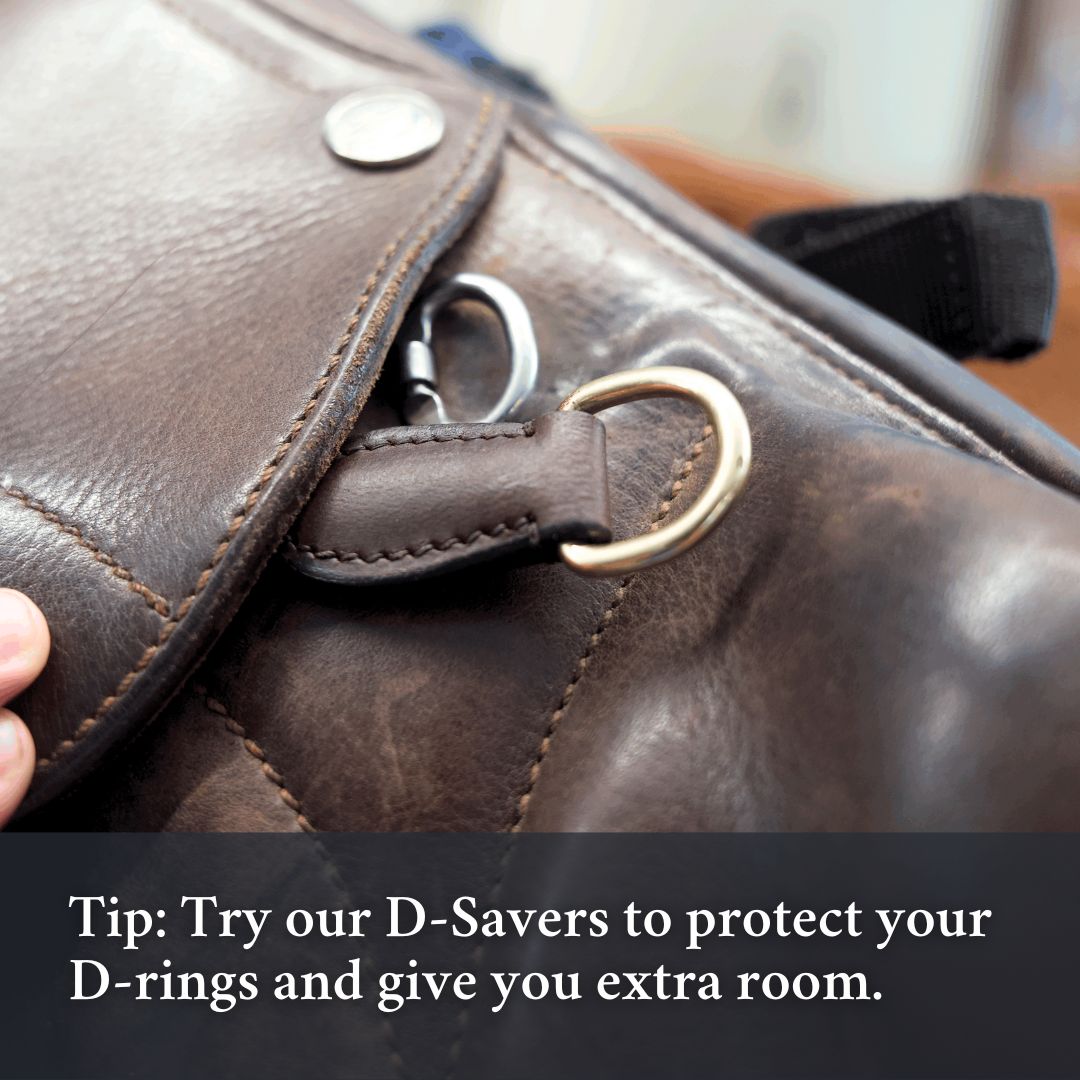 Close-up of a saddle D-ring with a leather cover, with a printed tip about protecting D-rings