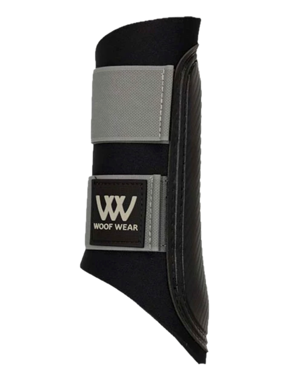 Woof Wear Club Brushing Boot in white on a horse's leg during schooling, showing open-front design, reinforced strike pad, and hook-and-loop closure