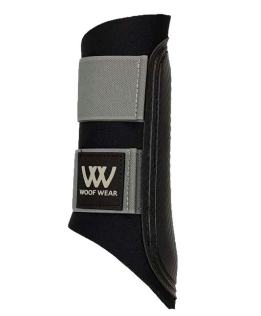 Woof Wear Club Brushing Boot in white on a horse's leg during schooling, showing open-front design, reinforced strike pad, and hook-and-loop closure