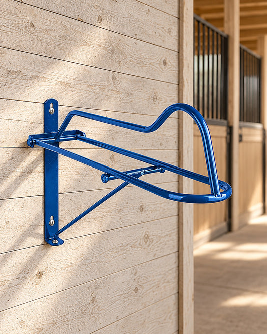 Blue folding wall saddle rack with gullet support, screwed to a weathered wooden barn wall