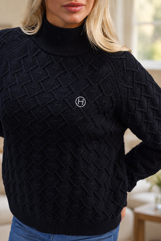 Woman in the black Swuni cable knit pullover in a country house sitting room