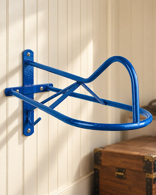 Blue wall saddle rack with gullet support and tack hook, screwed to a cream tack room wall